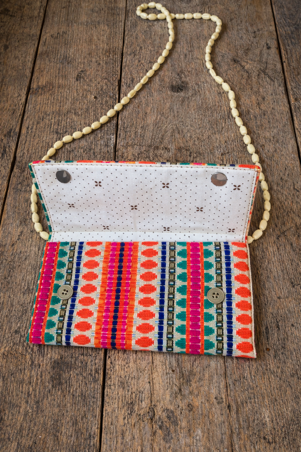 Open view of handwoven boho clutch showing patterned fabric and button closure