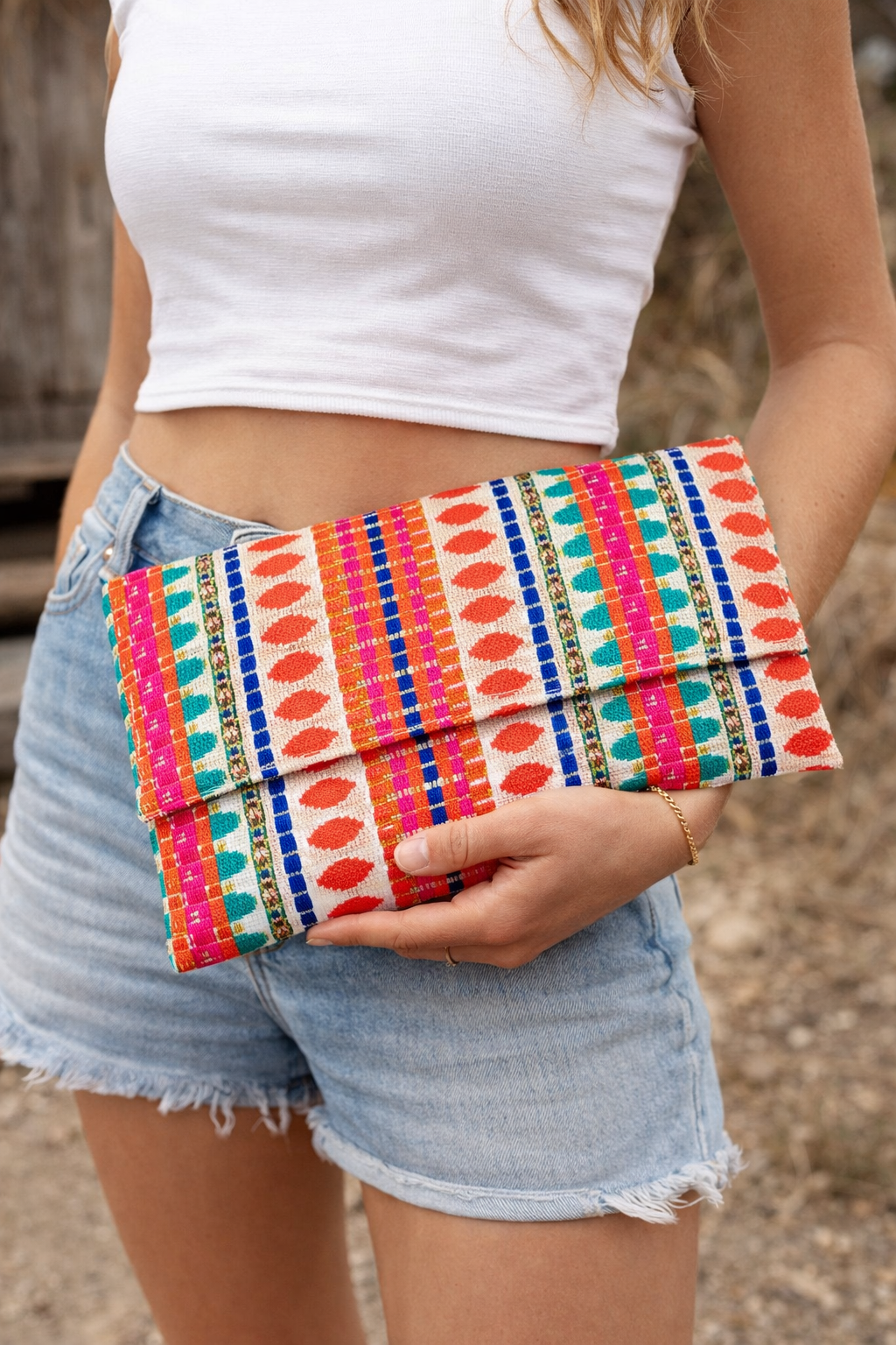 Model holding a colorful handwoven boho clutch purse with vibrant ethnic textile design