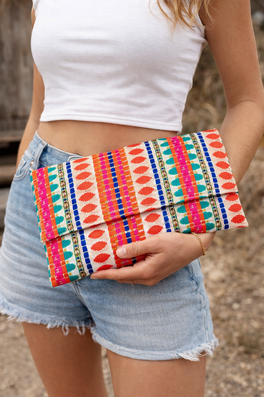 Model holding a colorful handwoven boho clutch purse with vibrant ethnic textile design