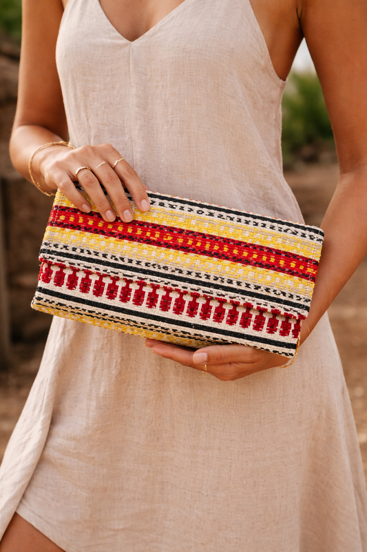 Close-up of colorful handwoven boho clutch purse with traditional red and yellow textile design