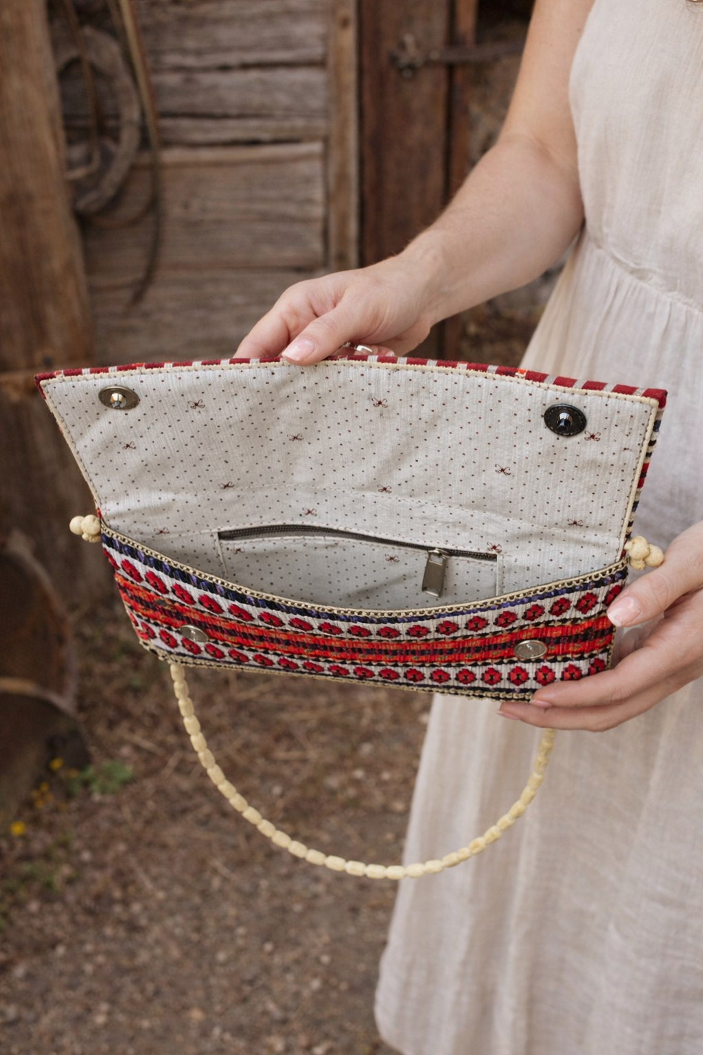 Inside view of boho clutch bag showing fabric lining, inner zip pocket, and button closure
